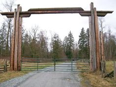 an old wooden gate in the middle of a dirt road