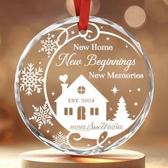 a glass ornament with a house and snowflakes in the background that says new home new beginnings, new memories