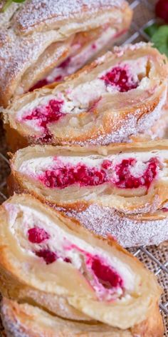 raspberry cream filled danish rolls on a cooling rack with fresh strawberries in the background