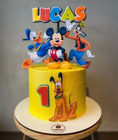 a mickey mouse birthday cake with goofy and pluto on top, surrounded by other disney characters