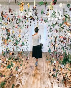 a woman standing in front of an art installation with flowers and plants on the walls