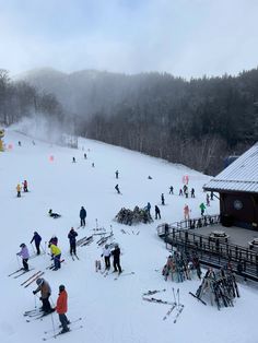 a group of people riding skis on top of a snow covered slope next to a building