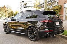 a black porsche cayen is parked on the street