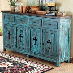 an old blue cabinet with crosses painted on the doors and drawers is in front of a rug