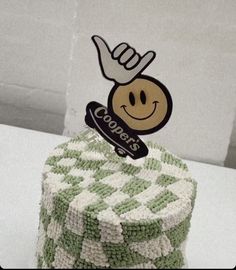 a green and white cake with a smiley face on it's top that has a fork sticking out of it