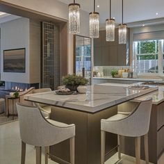 a large kitchen with an island and bar stools in the center, surrounded by windows