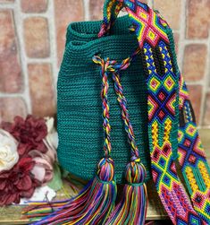 a green crocheted bag sitting on top of a wooden table next to flowers