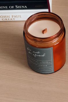 a candle sitting on top of a wooden table next to a stack of books and a book