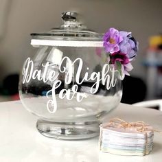 a glass jar with some flowers in it and a piece of paper on the table