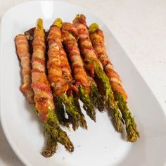 asparagus wrapped in bacon on a white plate