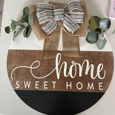 a wooden sign that says home sweet home with a bow hanging on the front of it