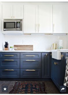 a kitchen with blue cabinets and gold pulls on the handles, along with a rug