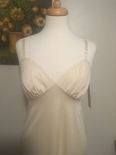 "Vintage new old stock Shadowline slip, 1950s beige slip dress, vintage full slip. Right out of the back storeroom! This new old stock unworn slip was in a ladies clothing store that had closed and has been sitting in the original box. The original tags are still attached. 'Pearl Beige' Bust x 34\" with adjustable straps to ensure a comfortable fit. Length x 48\" Beautiful silky Antron Nylon with a pretty delicate cross over neckline with lace around the bodice and bottom hem. New old stock in e Fitted Cream Camisole With Built-in Bra, Sleeveless Beige Slip Dress Bias Cut, Sleeveless Bias-cut Beige Slip Dress, Sleeveless Bias Cut Beige Slip Dress, Cream Camisole With Built-in Bra And Spaghetti Straps, Beige Fitted Camisole, Cream Fitted Camisole For Daywear, Fitted Cream Camisole For Daywear, Vintage Cream Slip Dress