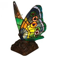 a stained glass butterfly sitting on top of a rock