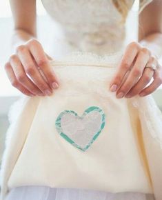 a woman holding onto a white dress with a blue heart on it