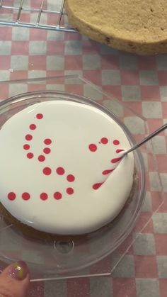 a person is cutting into a cake with red polka dots on the frosting and white icing