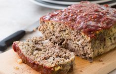 sliced meatloaf on cutting board with knife and plate in background