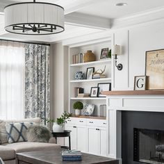 a living room filled with furniture and a fire place under a chandelier over a fireplace