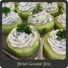 several cucumber bites with cream cheese and herbs on top are arranged in rows