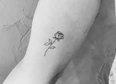 a black and white photo of a single rose tattoo on the left inner arm,