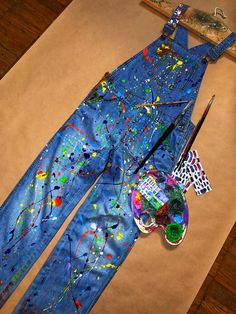 an artist's overalls with paint splattered on it and a brush