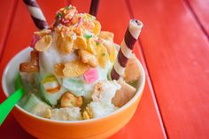 an orange bowl filled with ice cream and toppings on top of a red table