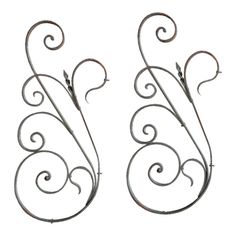 two metal brackets with swirly designs on the top and one has a long tail