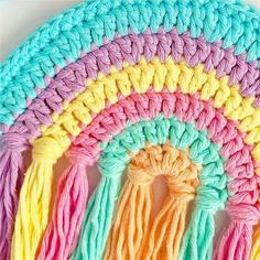 the crochet rainbow rug is made with yarn and has tassels on each side