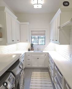 a kitchen with white cabinets and washer and dryer in the center, next to a window