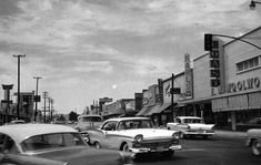 an old black and white photo of cars driving down the street