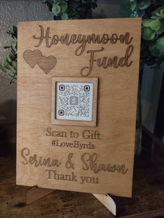 a wooden sign with a qr code on it that says honeymoon fund and someone's lovebirds