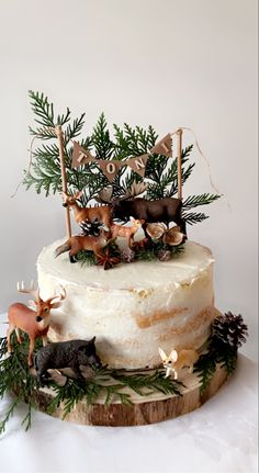 a white cake with pine branches and deer decorations