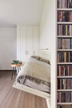 there is a bed in the middle of this room with bookshelves on both sides