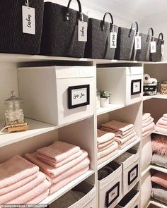 the shelves are filled with folded towels and other personal care items in black and white baskets