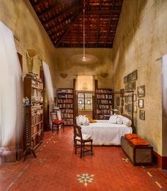 a room with a bed, chair and bookshelf in it's center