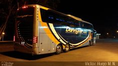 a double decker bus is parked on the side of the road at night with its lights on