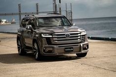 a silver suv parked on the side of a road next to an ocean and pier