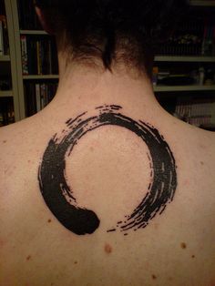 the back of a man's neck with a black circle tattoo on his chest