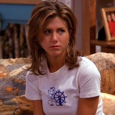 a woman sitting on top of a couch wearing a white shirt