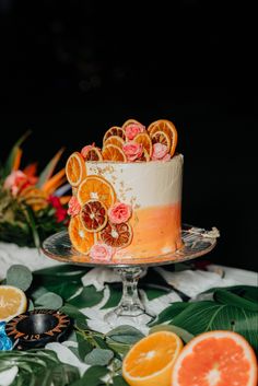 there is a cake with oranges on it and other decorations around the cake stand