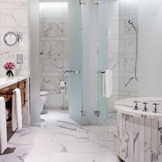 a bathroom with marble walls and flooring next to a bathtub in the corner