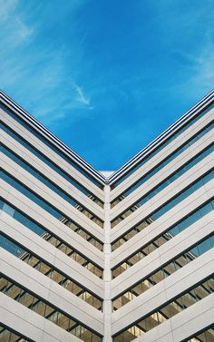 an upward view of the side of a building with windows and sky in the background