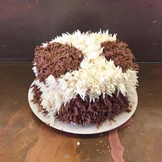 a cake with white and brown frosting sitting on top of a table