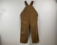 "Vintage 1970s or 80s brown duck denim overalls, workwear bib overalls. Has five front pockets, two hammer loops, side ruler pocket, left leg pocket a button fly, adjustable shoulder straps, triple stitched seams and riveted pockets and crotch rivet. Double thick knees. Made by Carhartt. About a size XL. Actual measurements are:  47\" at the waist  54\" hips  33\" thighs  29\" inseam  58\" overall length as pictured In very good condition with overall fading and stains." 1960s Boots, Overalls Brown, Carhartt Bibs, Dickies Overalls, Carhartt Vintage, Army Coat, Carhartt Overalls, Vintage Overalls, Vintage Workwear