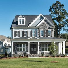 a large house with two story windows and white shutters on the front, surrounded by grass