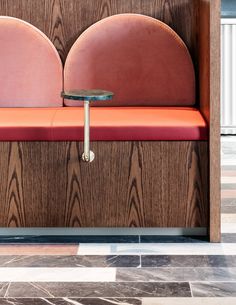 an orange bench sitting in the middle of a room with wood paneling on it