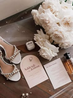 a bouquet of white flowers sitting on top of a table next to shoes and perfume bottles