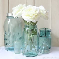 three jars with flowers in them sitting on a table