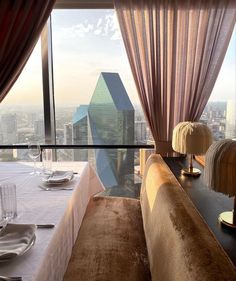 a long table with place settings on it in front of a window overlooking the city