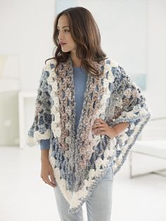 a woman wearing a crocheted shawl standing in a white room